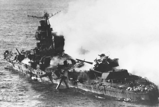 The heavily damaged Mikuma lies dead in the water shortly before sinking. The wreckage of an American Vought SB2U Vindicator dive bomber lies on top of the aft gun turret. (US Navy)